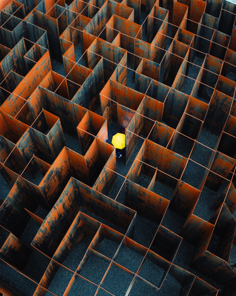 Pessoa com um guarda-chuva procura a saída de um labirinto na Bélgica - Mel Zagers