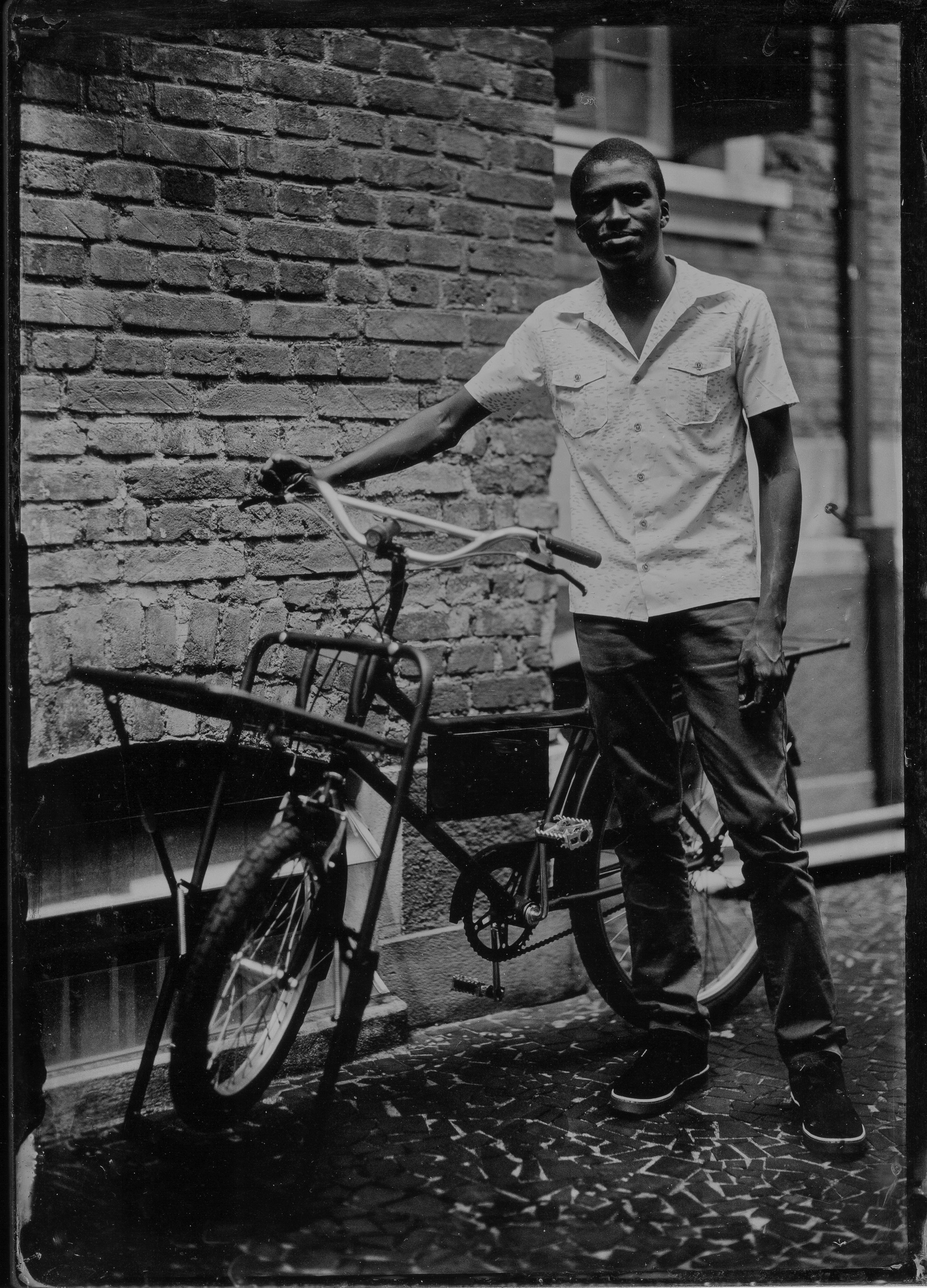 Retrato de um entregador e sua bicicleta de entregas feito por Roger Sassaki na região central da cidade de São Paulo 