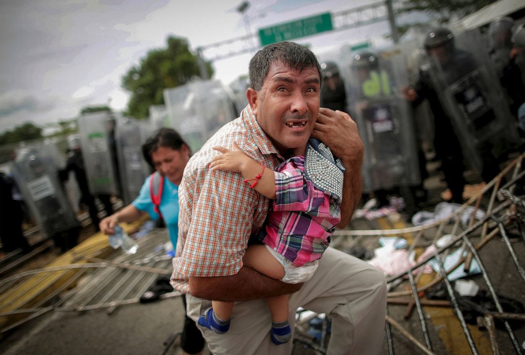 Um hondurenho protege o filho depois que outros migrantes invadiram um posto fronteiriço na Guatemala, em Ciudad Hidalgo, México