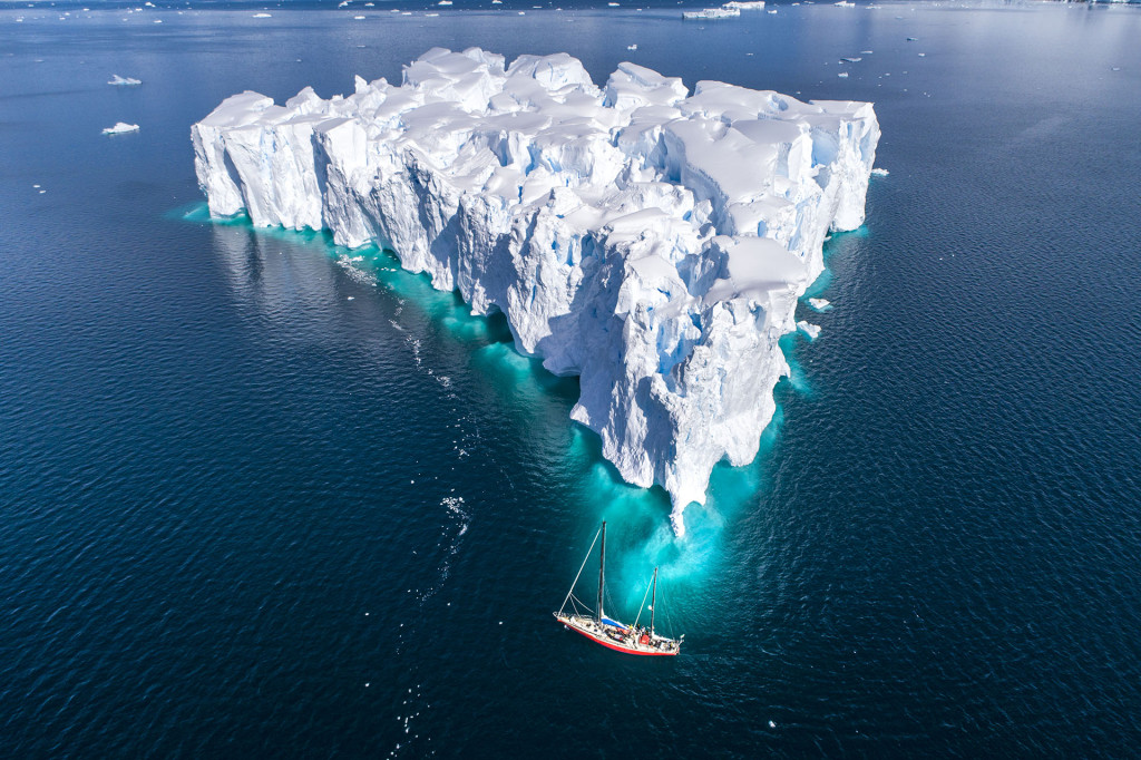 Em foto com drone, o veleiro Fernande próximo a um iceberg no formato do mapa do Brasil. Foto: André Dib