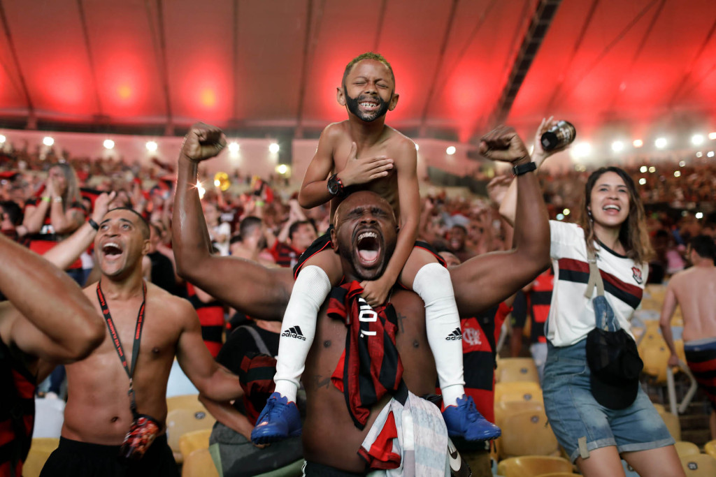 In this Nov. 23, 2019 photo, Flamengo soccer fans cheer a goal scored by Gabriel against Argentina's River Plate in the Copa Libertadores final match, broadcast on a giant screen at a watch party at the Macarena Stadium, in Rio de Janeiro, Brazil.